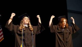 2 graduates signing at commencement